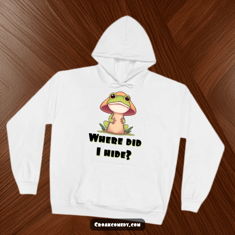 Funny frog hoodie, featuring a curious frog peeking from behind a large mushroom, offering a cozy and mysterious vibe.