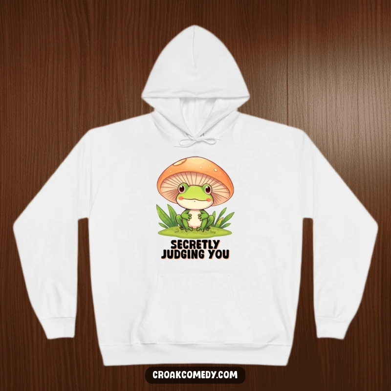 Funny Frog Hoodie featuring a frog peeking with a smile from behind a mushroom, conveying playful curiosity.
