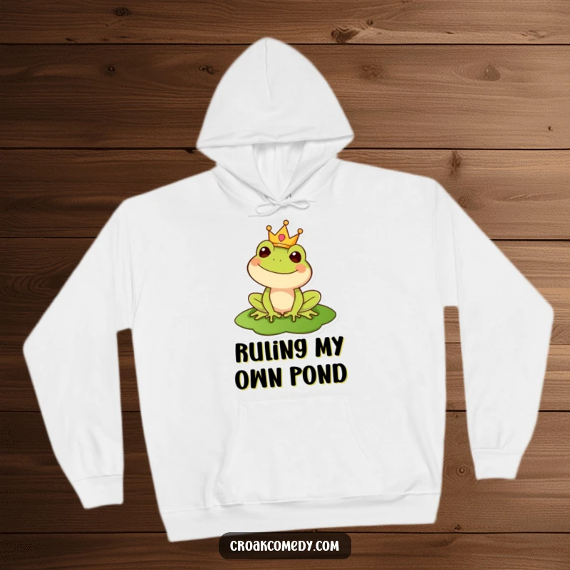 Funny hoodie depicting a regal frog wearing a crown on a lily pad, offering cozy comfort with a touch of majesty.