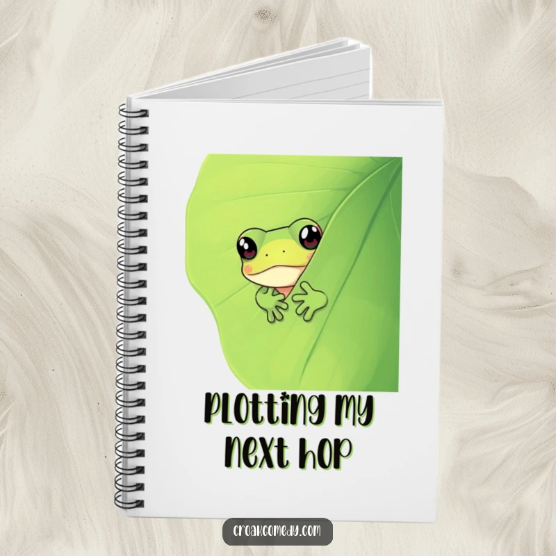 Funny frog peeking from behind a green leaf, providing a humorous and engaging cover for this versatile notebook.