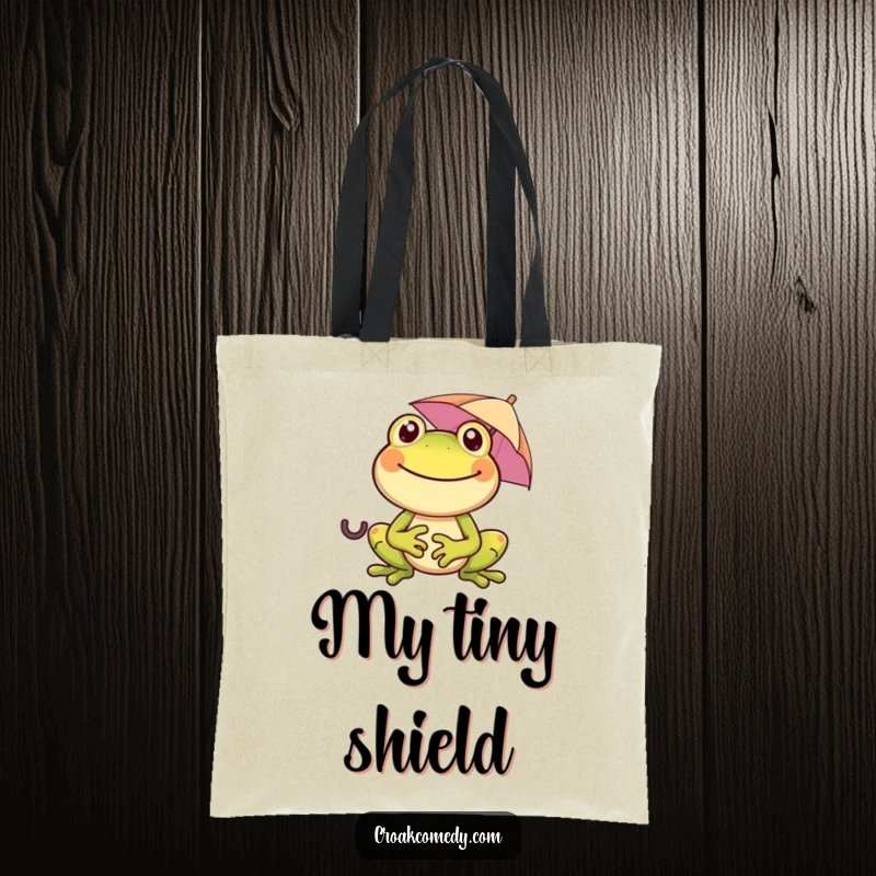 Funny frog with a wide smile, holding a tiny umbrella, on a tote bag, perfect for carrying essentials with a humorous touch.